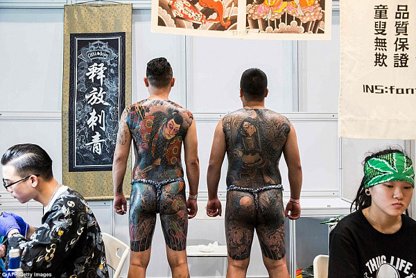 Bare faced cheek: Two confident attendees display their tattoos in a stall at the Hong Kong China International Tattoo Convention showing off their near entire body art with a Japanese samurai as the central focus of their work