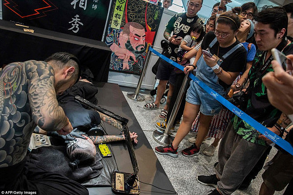 Lying still: With his hair tied up in a samurai style, the subject clasps his hands together in pain while dozens of attendees watch on