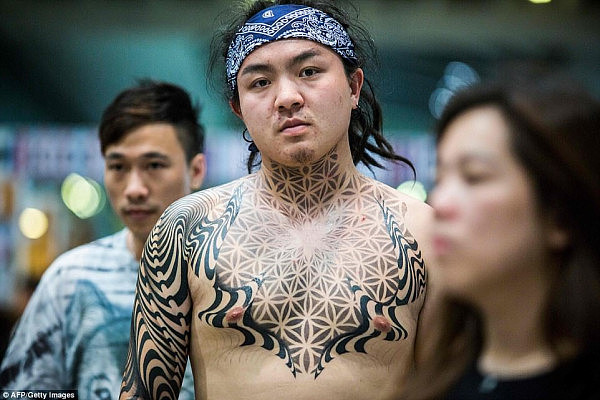 Tripy look: An attendee with an optical illusion pattern of tattoos across his chest and shoulders proudly displays his absorbing artwork 