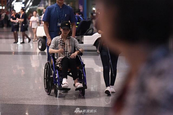 胡静坐轮椅专人推出机场，手上的拐杖亮了，可她的表情才让人担心