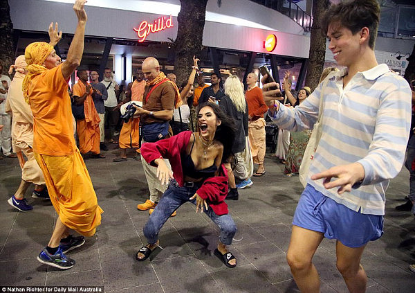 Fitting in: Orange was the colour of the night, as one woman danced with what appeared to be Hare Krishnas 