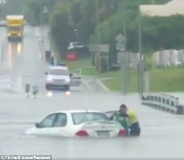 A heroic man has been filmed carrying an elderly woman from a submerged car before carrying her to safety through floodwaters