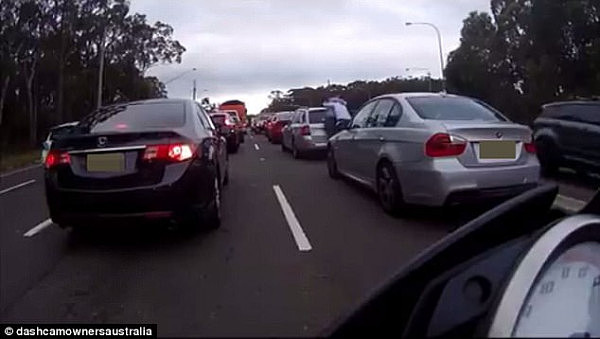 The shocking moment two suited men began fighting in the middle of a traffic jam in Sydney has been caught on camera (pictured)