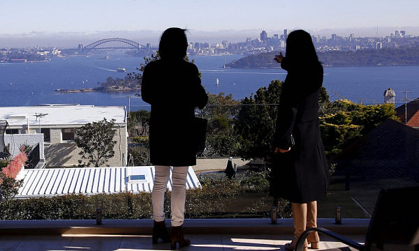 A real estate agent and potential Chinese home buyer from Shanghai look over the Sydney Opera House and Harbor Bridge in the Sydney suburb of Vaucluse, Australia, July 11, 2015. Photo: Reuters/David Gray
