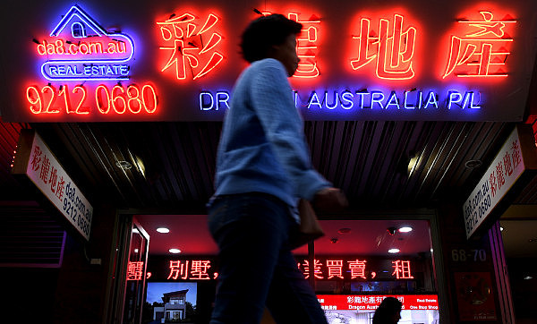 A woman walks by Chinese language advertisements for Australian property in Sydney's Chinatown on June 21, 2017. Photo: AFP/William West 