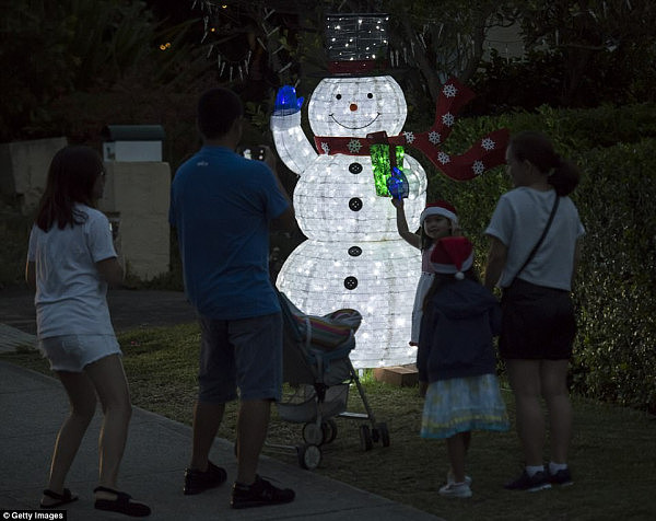 The city's only saving grace is its suburban homes, where families have gone all out in competition for their streets' most festive houses (pictured are Mosman residents enjoying their neighbours' decorations)