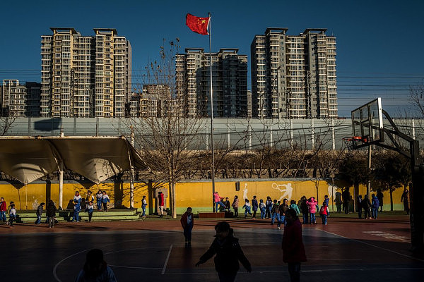 国旗在学校的院子里飘扬。一名研究中国城乡差距的华盛顿大学教授说，打击为移民开设的学校“基本上是毁掉整整一代孩童”。