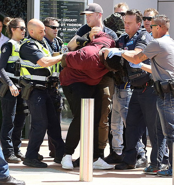 A teenager is restrained by several police outside Tarneit Central shopping centre during a series of violent confrontations which resulted in three arrests on Wednesday afternoon