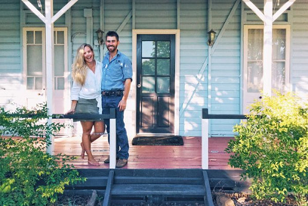 Sam Hart and Alina Rasmussen stands smiling on the verandah of their house at Blackall in central-west Queensland.