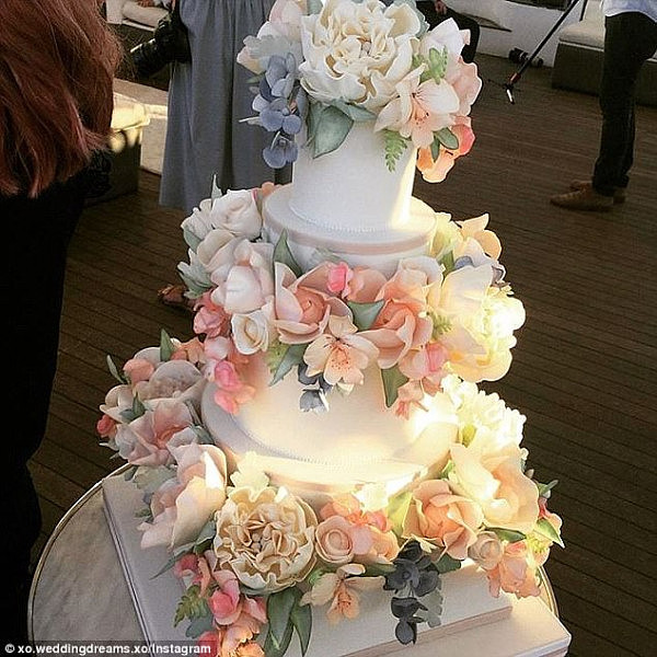 The floral theme continued onto their three-tiered wedding cake, which featured soft orange and yellow flowers