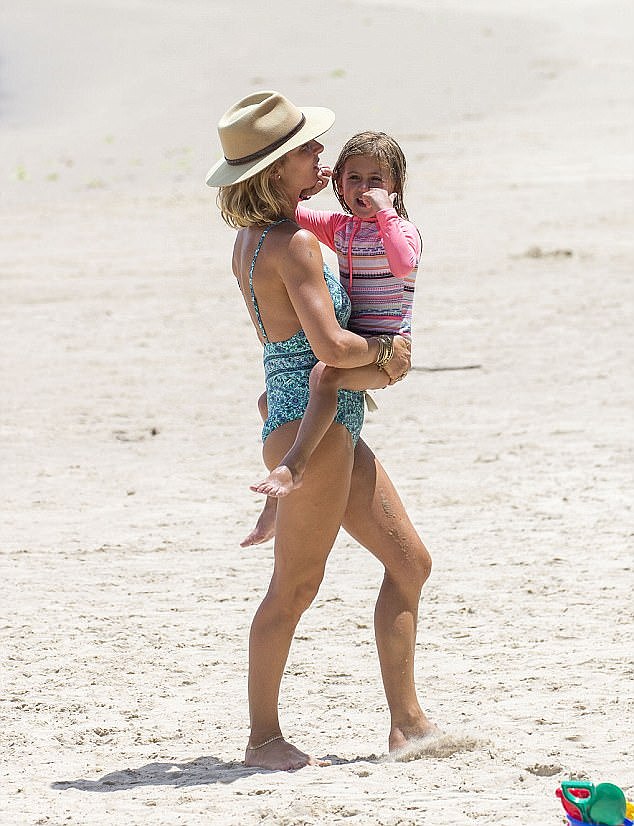 Sizzling! Donning a blue and teal one-piece, Elsa sizzled on the sand as she held India Rose 