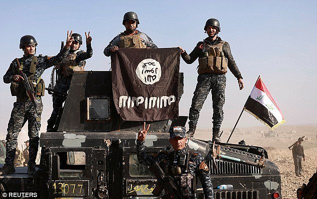 Federal police members pose with an Islamic State (IS) flag along a street of Albu Saif which was recaptured from Islamic State, south of Mosul, Iraq