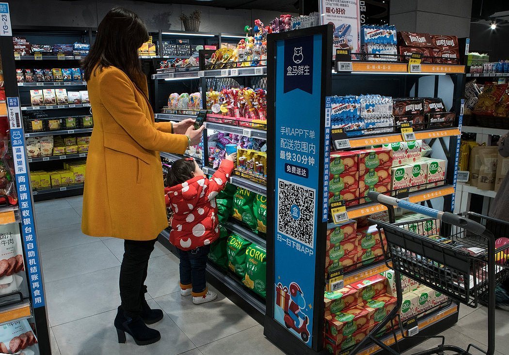 一名购物者在阿里巴巴旗下的便利商店盒马鲜生用智能手机扫描商品。这家公司正在其商店里实验自动化购物的方式。