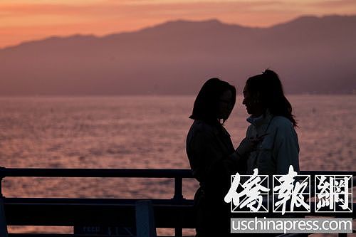 夕阳下站在圣塔莫尼卡海边栈桥上的两名华裔女青年。（侨报记者邱晨摄）