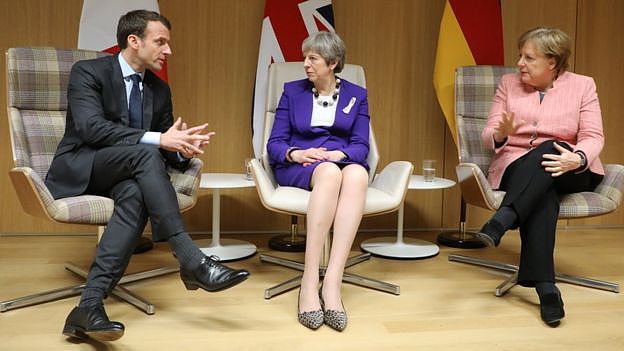 UK Prime Minister Theresa May (C), German Chancellor Angela Merkel (R) and French President Emmanuel Macron (L) give a press conference on March 22, 2018