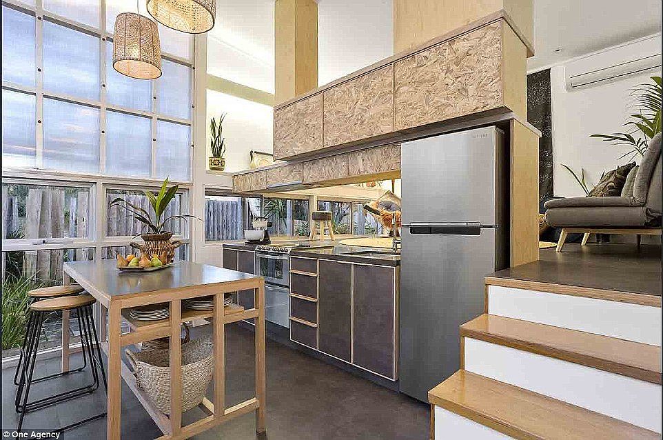 The refurbished house has a new custom kitchen and dining area while timber stairs lead up to the living area