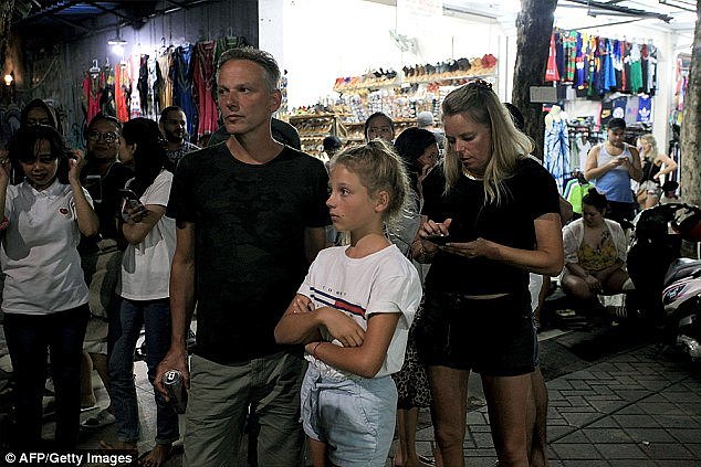 A distressed family of tourists stand out on the street in Bali after being evacuated from their hotel