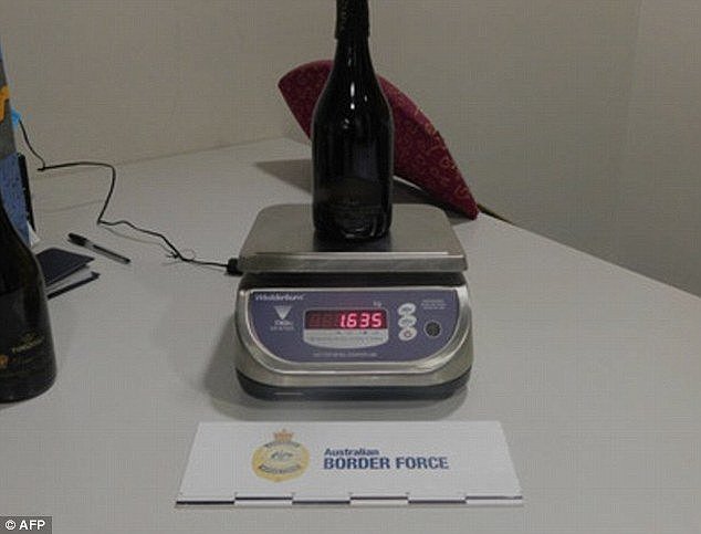 A man has been caught allegedly attempting to smuggle 3.2kg of cocaine into Australia (pictured is one of the wine bottles allegedly carried by the man)