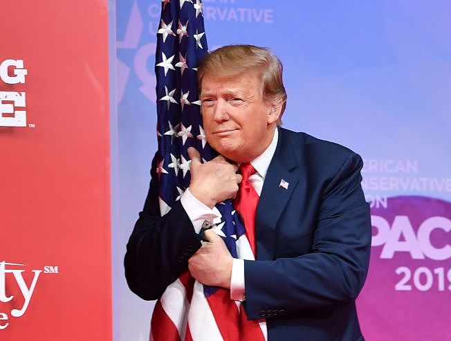 川普总统出席保守派政治行动大会，上台拥抱美国国旗。 (Getty Images)