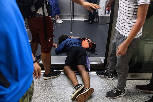 反送中示威者5日发动香港全市大罢工。 一名示威者5日一早在躺在地铁车门，阻止发车。 (Getty Images)