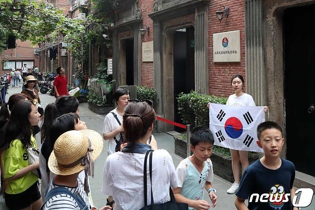 14日，一名韩国女游客在临时政府旧址前举太极旗留念。（news 1）