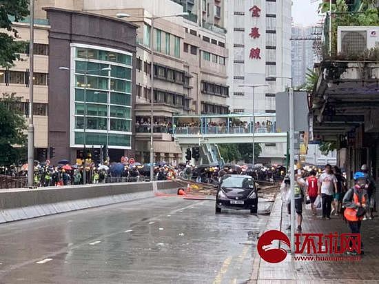 （25日17时30分左右，示威者们在荃湾杨屋道设置路障，并不断用敲击木棍、照射镭射灯挑衅警察。水炮车已在荃湾沙咀道待命。摄/陈青青）