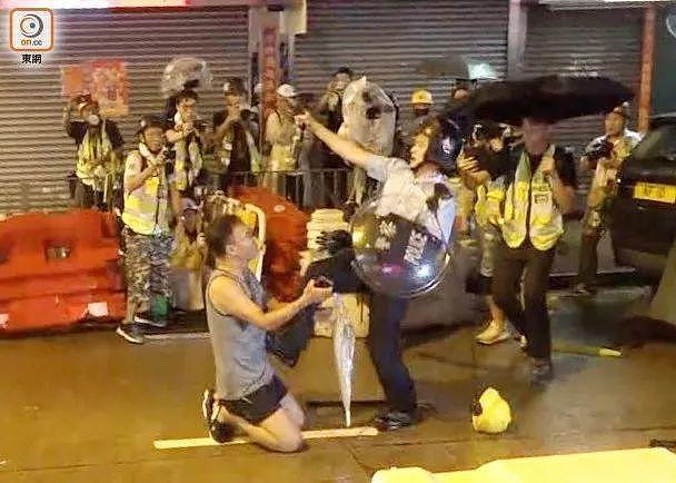 （部分媒体传出的持枪警员踢开跪地示威者。图源：香港“东网”)