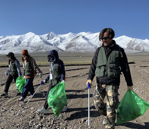 2019年7月，娱乐明星胡歌在玉珠峰下、青藏公路旁，参与捡垃圾活动。图片来源：同行的志愿者提供
