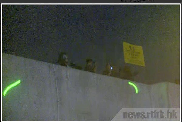  示威者用镭射笔照射军营顶楼上的军人，解放军“首度”举出黄旗警告。香港电台