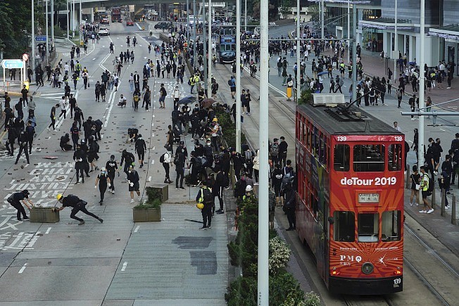 香港因「反送中」导致的警民冲突11日加剧升温，这个亚洲金融中心在数月的无解抗争中，原本自豪的社会与经济活动几近瘫痪。 图为抗争后，一辆挂着「2019年绕道」标示的红色双层巴士，在抗争后行过不少黑衣人聚集、满目疮痍的街道。 (美联社)

