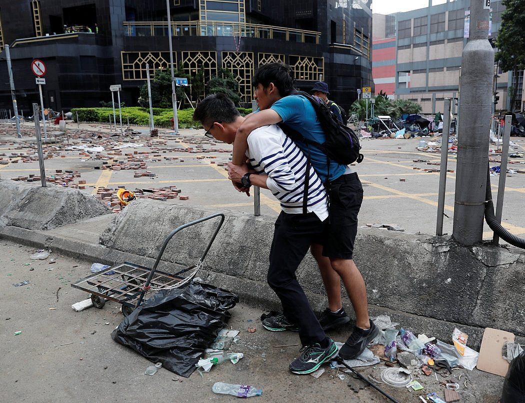 一名男子背着儿子，在香港理工大学外等待救护车。