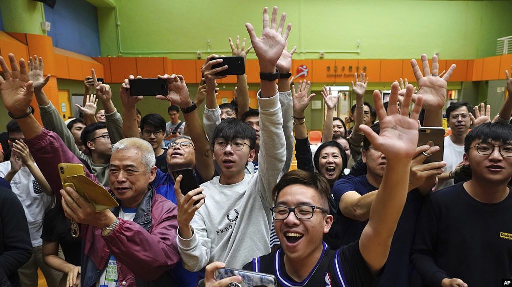 香港选民在他们支持的一名民主派候选人在区议会选举中获胜后举手欢呼。（2019年11月25日）