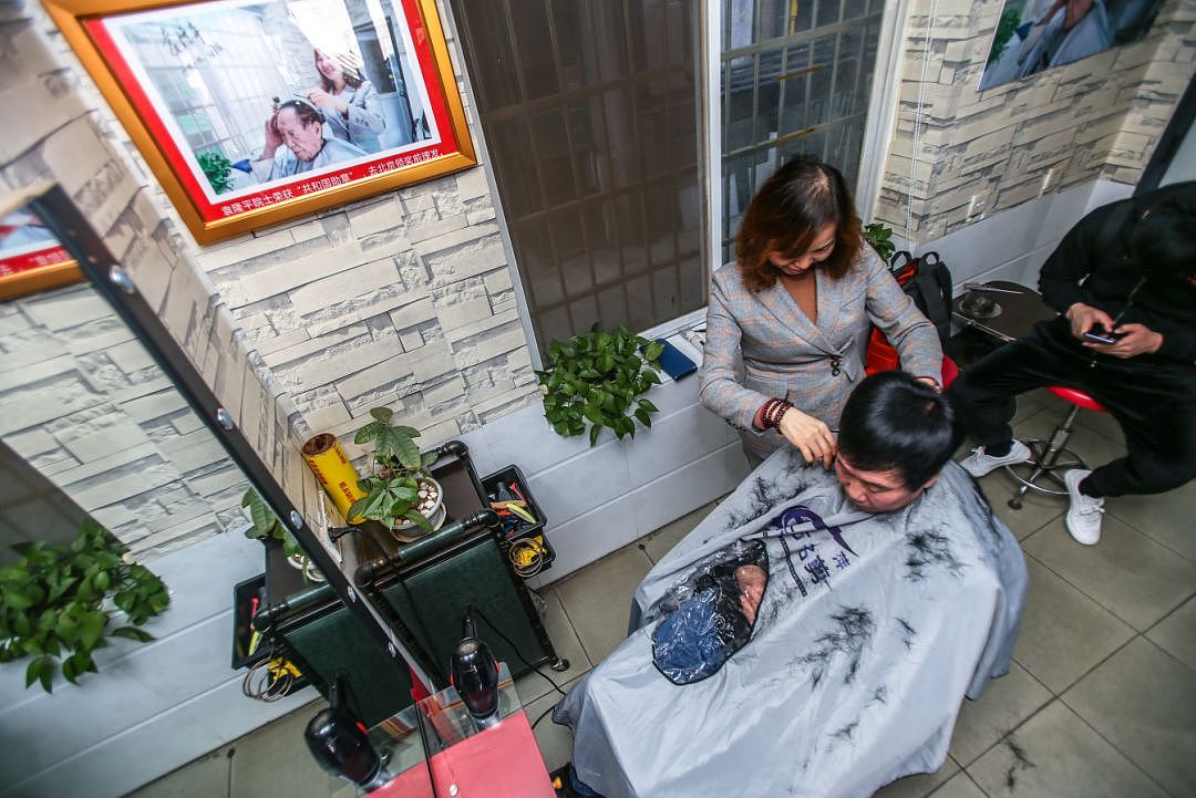 12月10日，位于红园东路的曹氏名剪理发店内，店主曹小平正在为顾客理发，因为店面非常小。所以顾客一多店内就变得非常拥挤。图 记者/张云峰