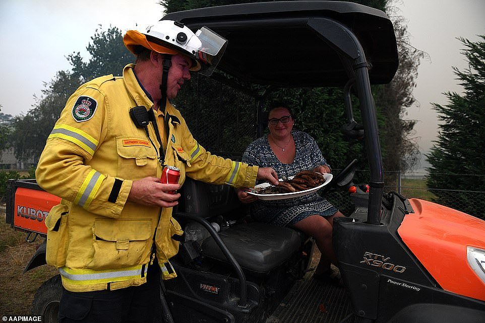 Local resident Andrea Galea brings sausages for NSW Rural Fire Service crews protecting properties north of Sydney