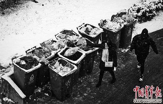 12月16日，北京朝阳区一小区内，住户将垃圾袋投放到路边的垃圾桶。中青报·中青网见习记者 张玉佳/摄