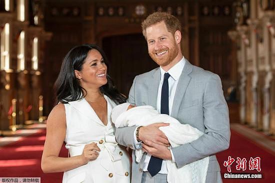 资料图：英国哈里王子和梅根夫妇抱着刚出生的儿子在温莎城堡的圣乔治大厅合影。