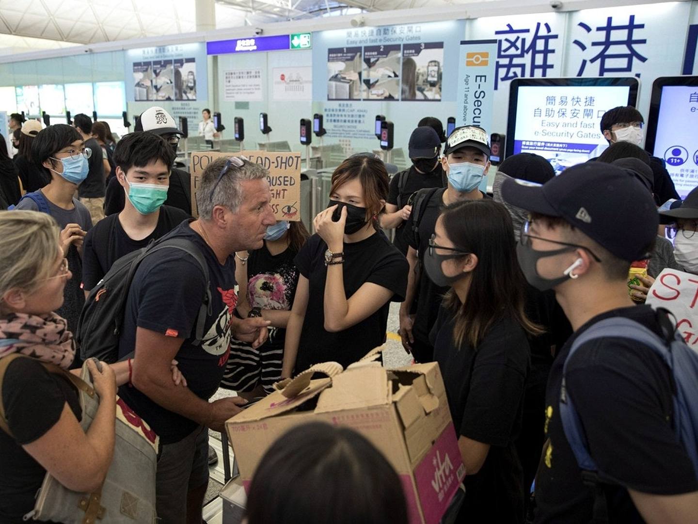 2019年8月13日，香港机场旅客们与试图通过香港国际机场登机口的抗议者发生争执。(美联社)