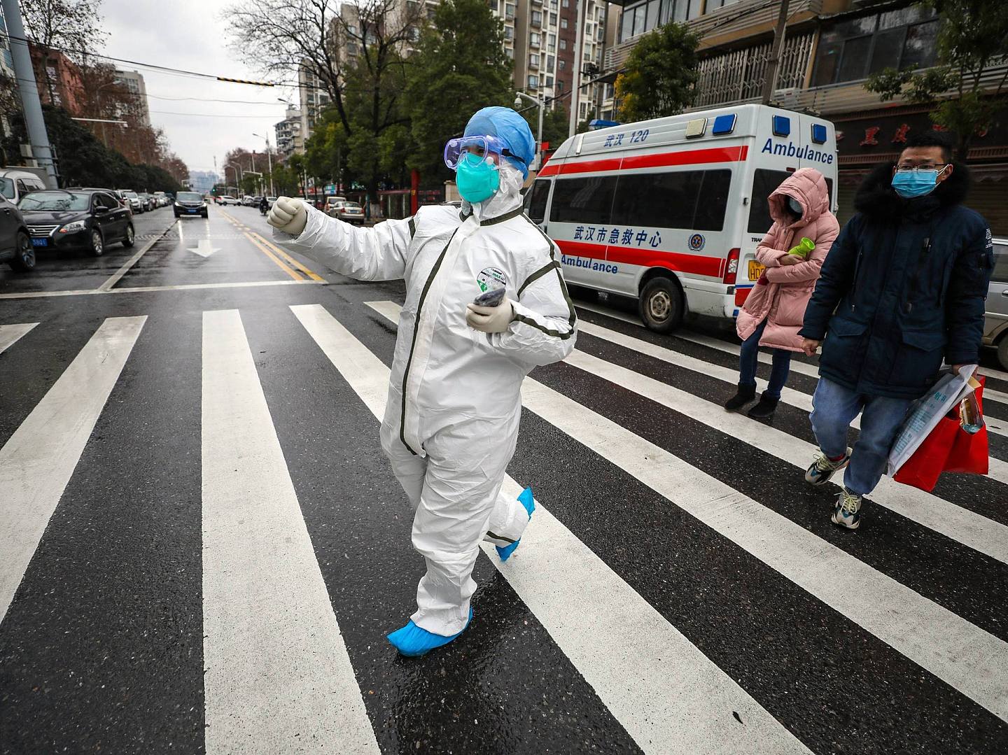 新型冠状病毒感染的肺炎疫情迅速蔓延全中国，图为1月26日湖北武汉市一名身穿防护服的医护人员带领病人前往一家医院。（AP）