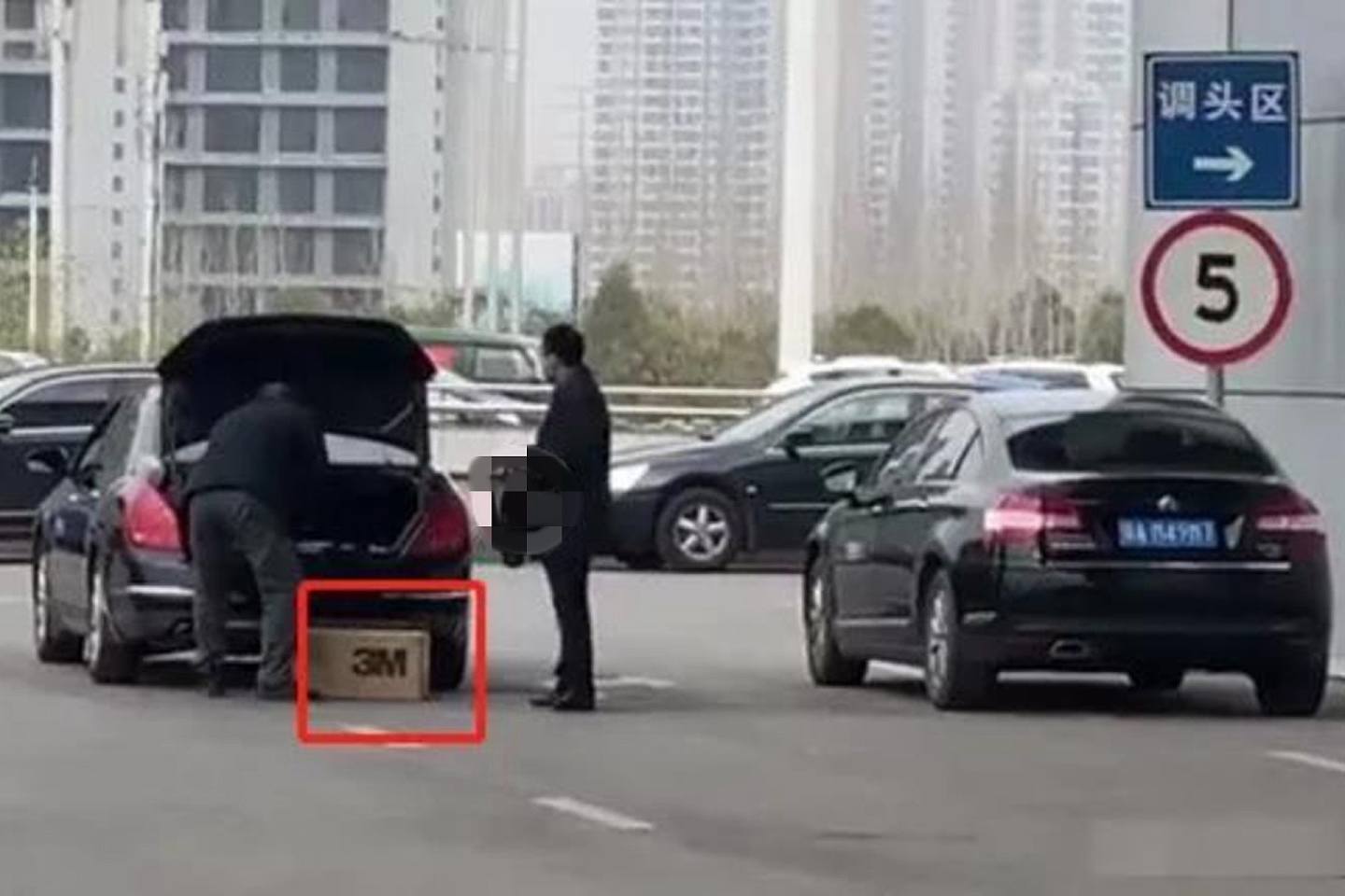 网络视频拍到的男子将提取的整箱口罩准备放到公务车后备箱内。（微博视频截图）