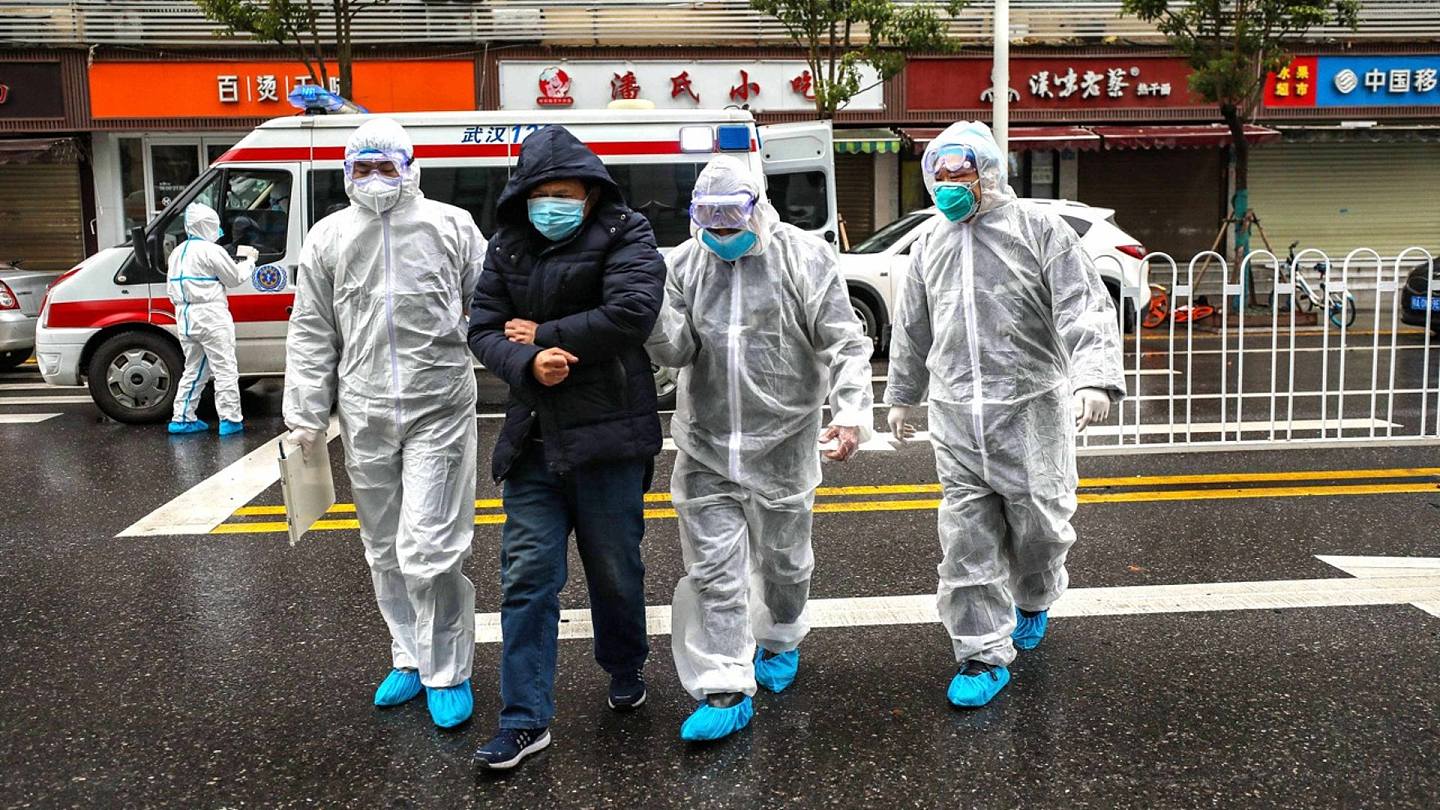 2020年1月26日，在中国湖北省武汉市，身穿防护服的医务人员在一辆救护车附近帮助一名病人。（AP）