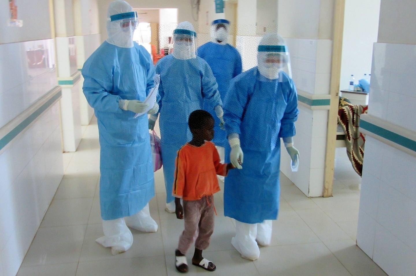 2014年10月11日，在塞拉利昂首都弗里敦，来自中国的医护人员护送埃博拉留观患者进入病房。（新华社）