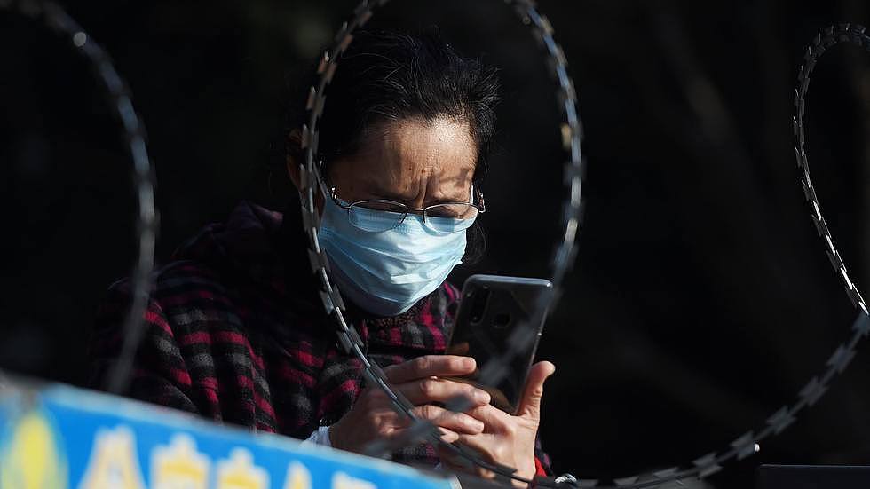 2月22日，武汉，一位女士在铁丝网围住的居民楼前打电话。