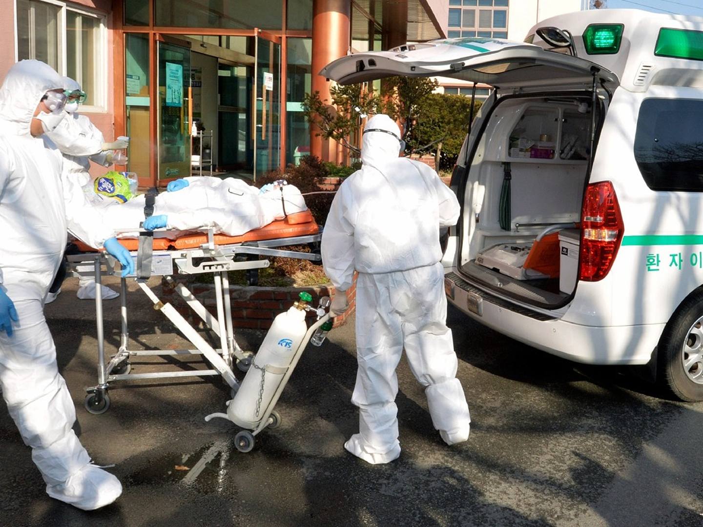 2月21日，韩国医护人员穿戴防护装备，将一名疑似感染新型冠状病毒的患者抬上救护车。韩国当天报告了100起新的病毒感染病例，使感染病例总数达到204例，人们担心疫情正在失去控制。（AP）