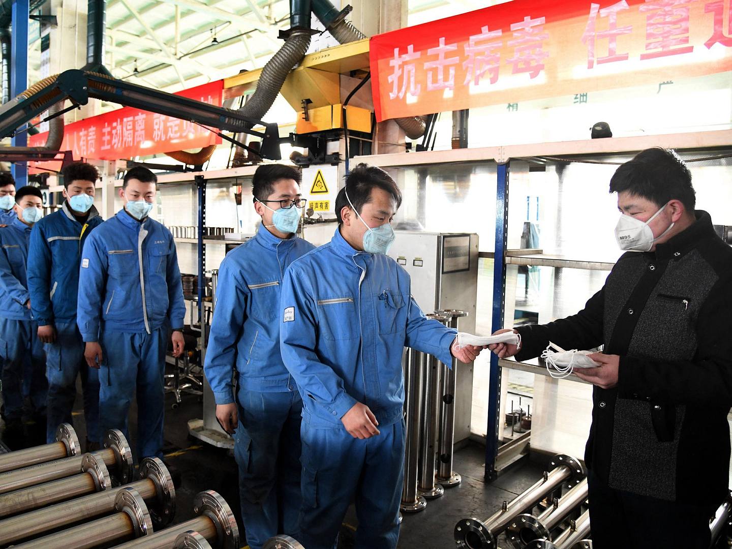 2020年2月9日，中国青岛一家工厂的工人在排队领取口罩准备复工。（新华社）