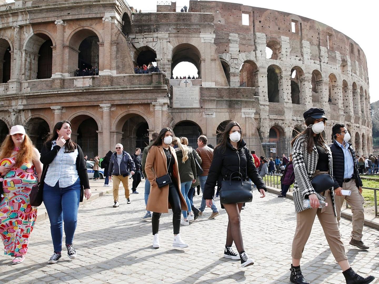 2月25日，游客们戴着防护口罩走过意大利罗马的圆形大剧场。（Reuters）