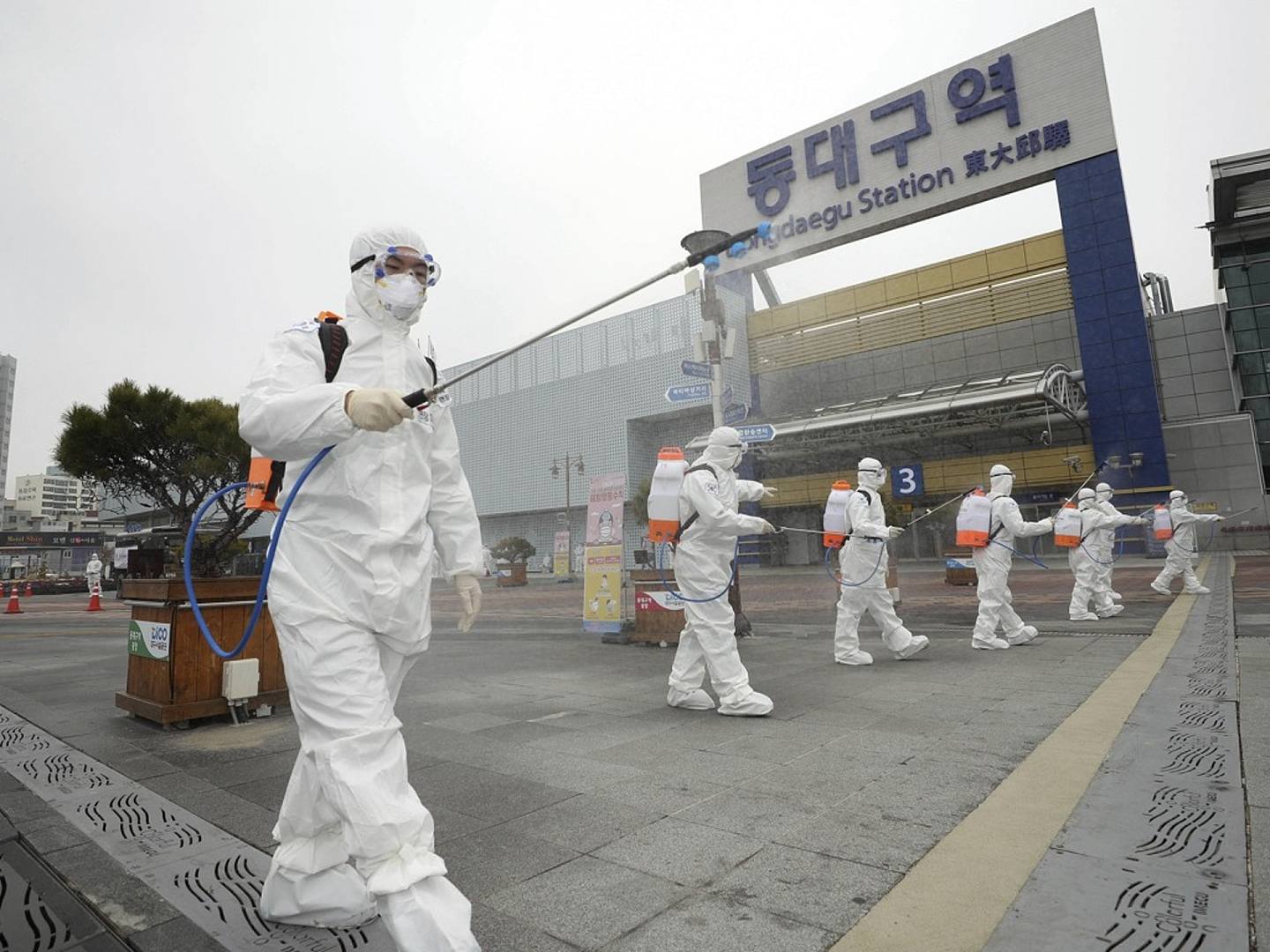 在韩国大邱的东大邱火车站，身穿防护服的士兵们正在喷洒消毒剂，防止新型冠状病毒的传播。(AP）