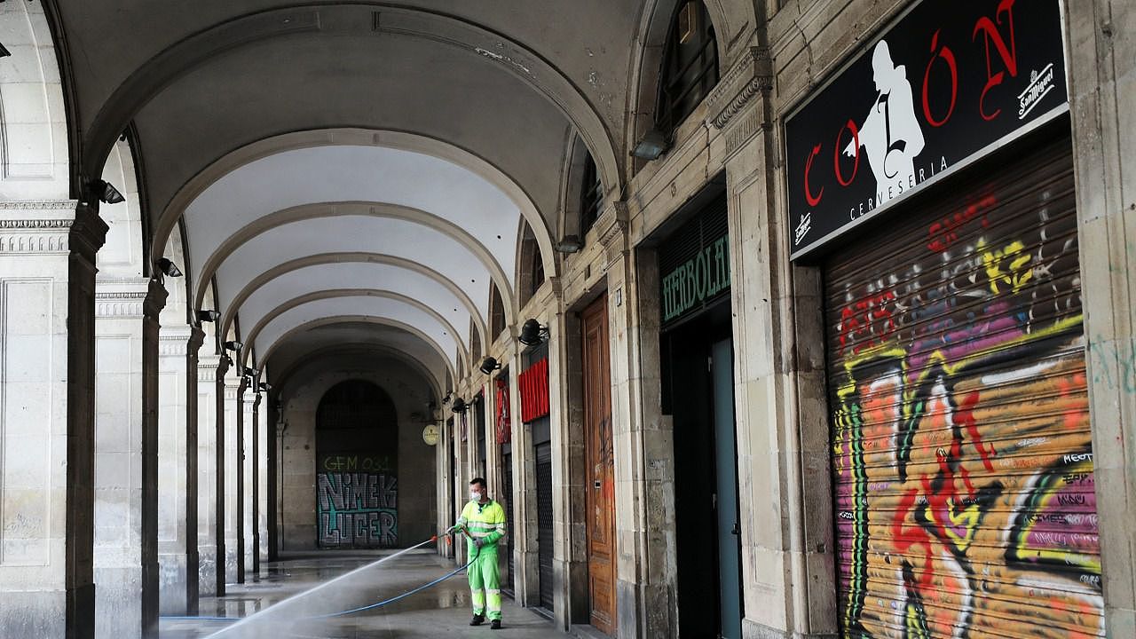 3月14日在西班牙巴塞罗那一名工人戴着防护口罩在清洗空无一人的广场。（路透社）