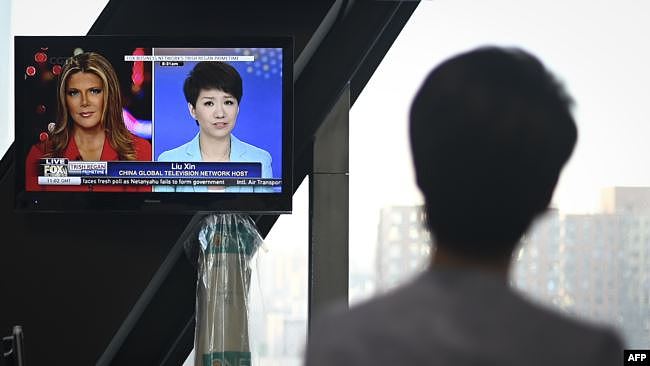 中国官方的英文电视频道中国环球电视网（CGTN）主播刘欣2019年5月30日在北京的中央电视台总部观看电视屏幕上播放的她接受美国福克斯商业频道主持人翠西·里根访谈的画面。