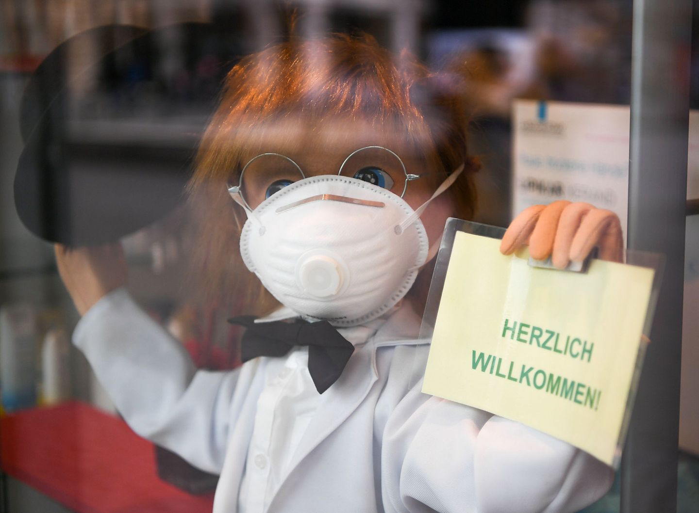 随着疫情在全球多地爆发，口罩等医疗物资供需紧张问题更加突出。图为3月8日，在德国法兰克福，一家药店门口摆放着戴口罩的卡通人偶。（新华社）