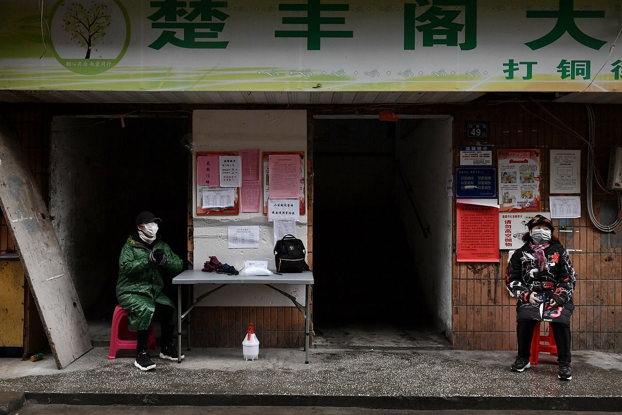 2020年2月28日，武汉志愿者戴着口罩在一座居民楼的入口处站岗。（路透社）